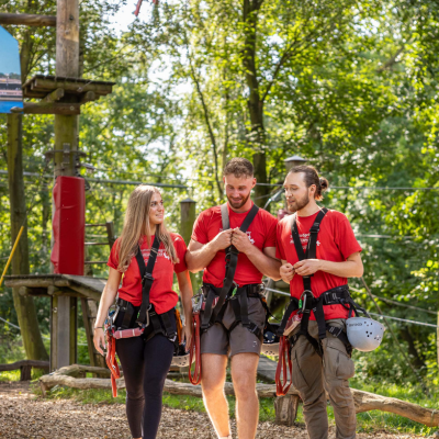Drei junge Leute stehen gemeinsam in Kletterausrstung im Kletterpark