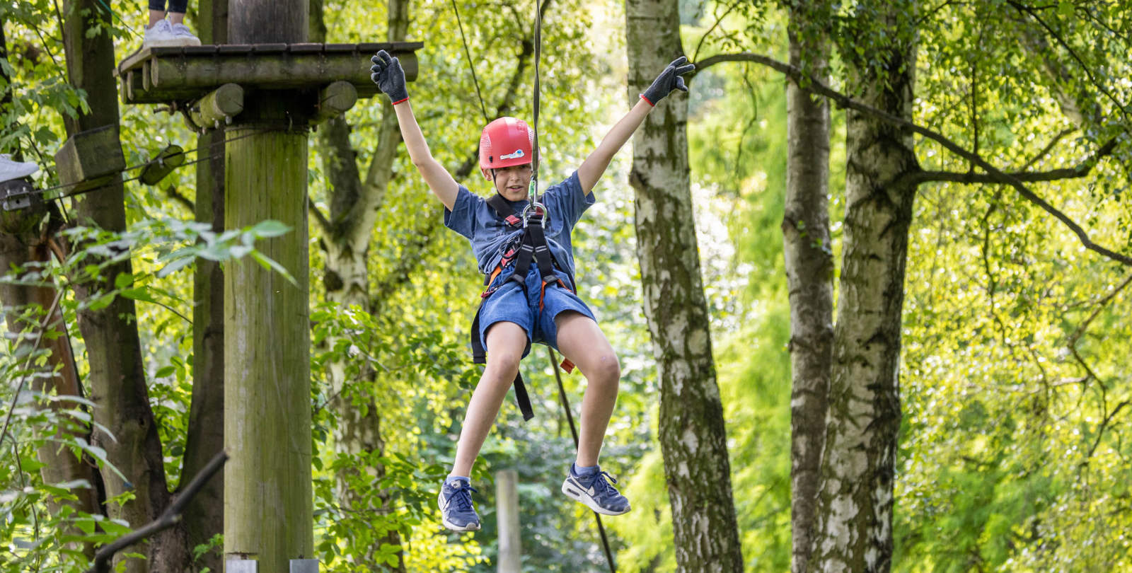 Junge schwebt in seiner Kletterausrstung in der Schwebebahn