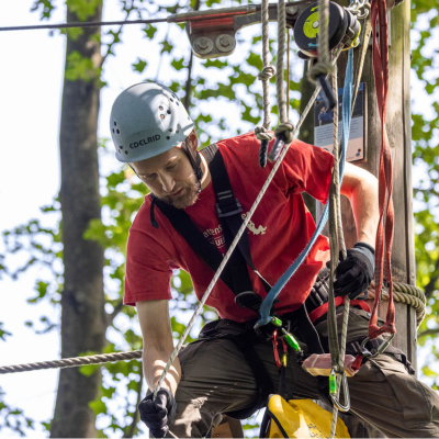 Junger Mann prft die Sicherung in einem Kletterelement
