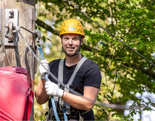 Mann im Halbportrt in Kletterausrstung lacht in die Kamera