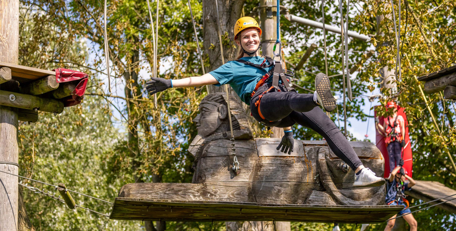 Junge Frau schwebt in ihrer Seilsicherung und schaut lchelnd in die Kamera